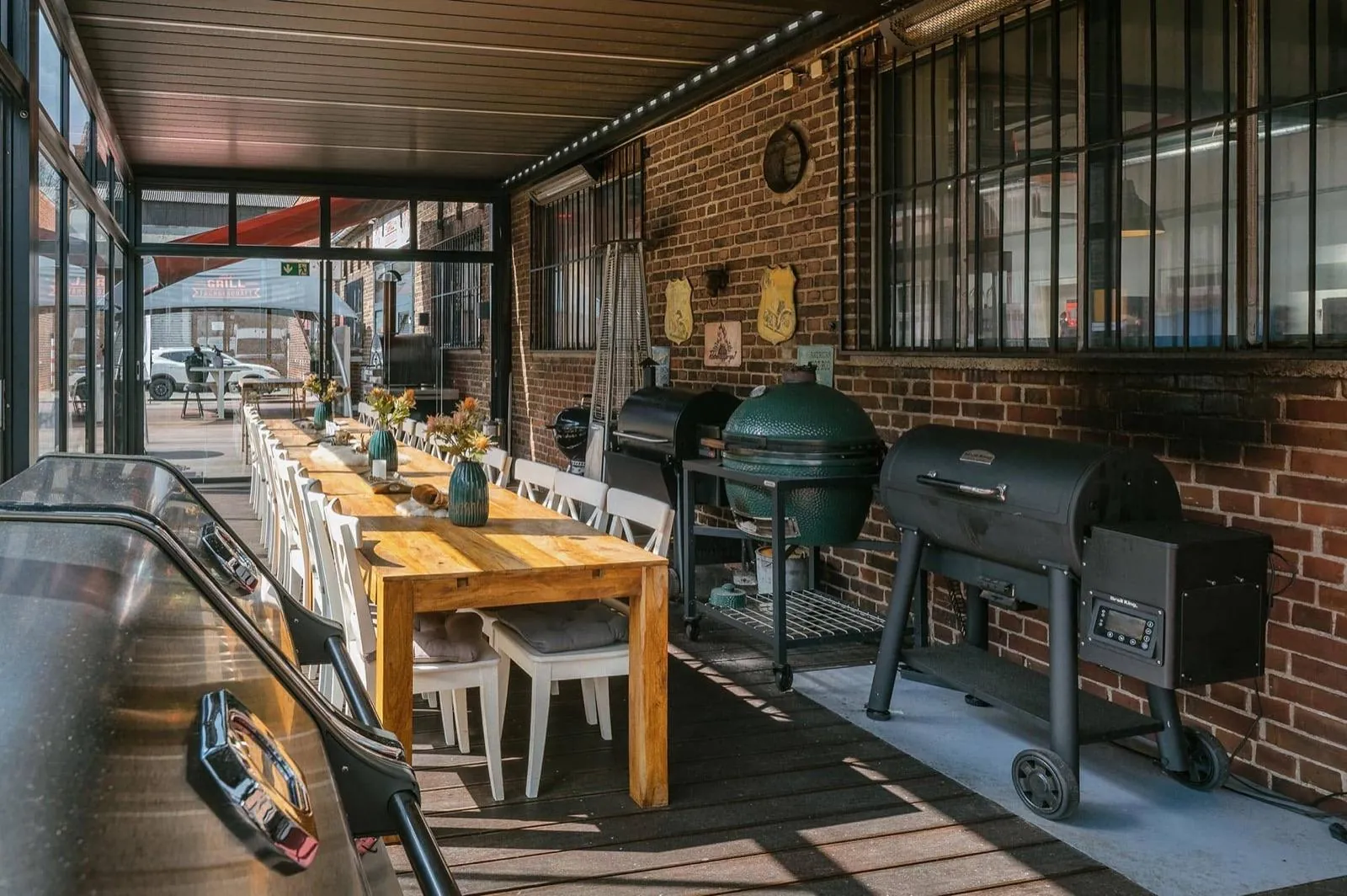 Überdachte Grillterrasse mit großen Grills und gedeckter Holztafel